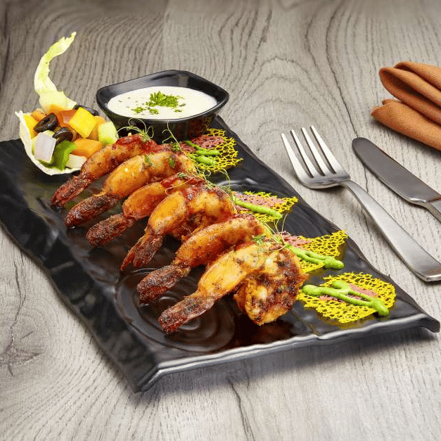 A plated dish with sauce and garnishes, served on a black rectangular platter - The Citrine