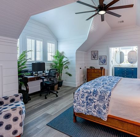 Spacious bedroom with a wooden bed, blue accents, and a ceiling fan | Abaco Inn
