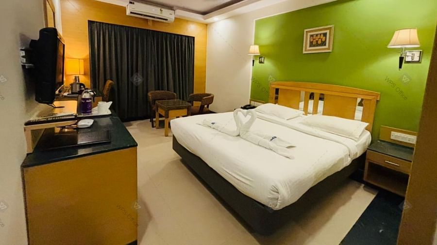 Executive room with green feature wall and plush bedding at Hotel Dr Rajkumar International.