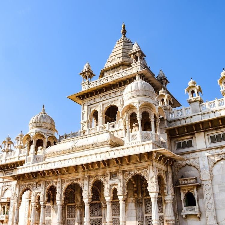 Facade of Jaswant Thada, one of the best Jodhpur tourist places, with intricate detailing on the walls and blue sky in the background