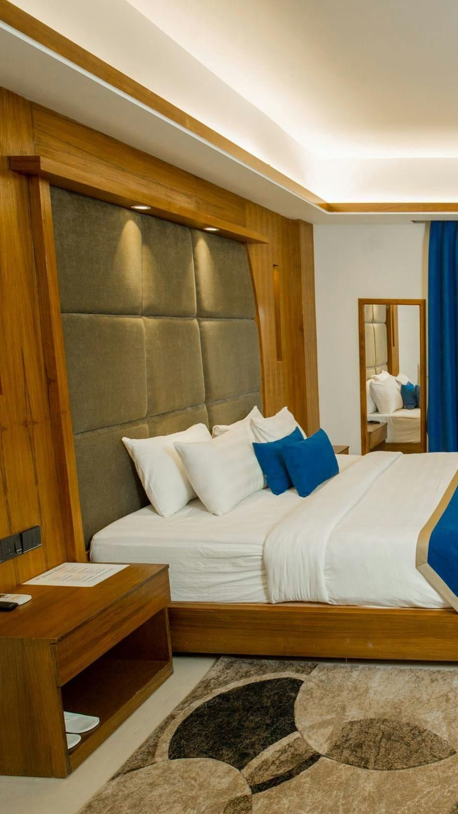 A spacious room featuring a large bed, a practical desk, a cosy seating area, and stylish modern decor