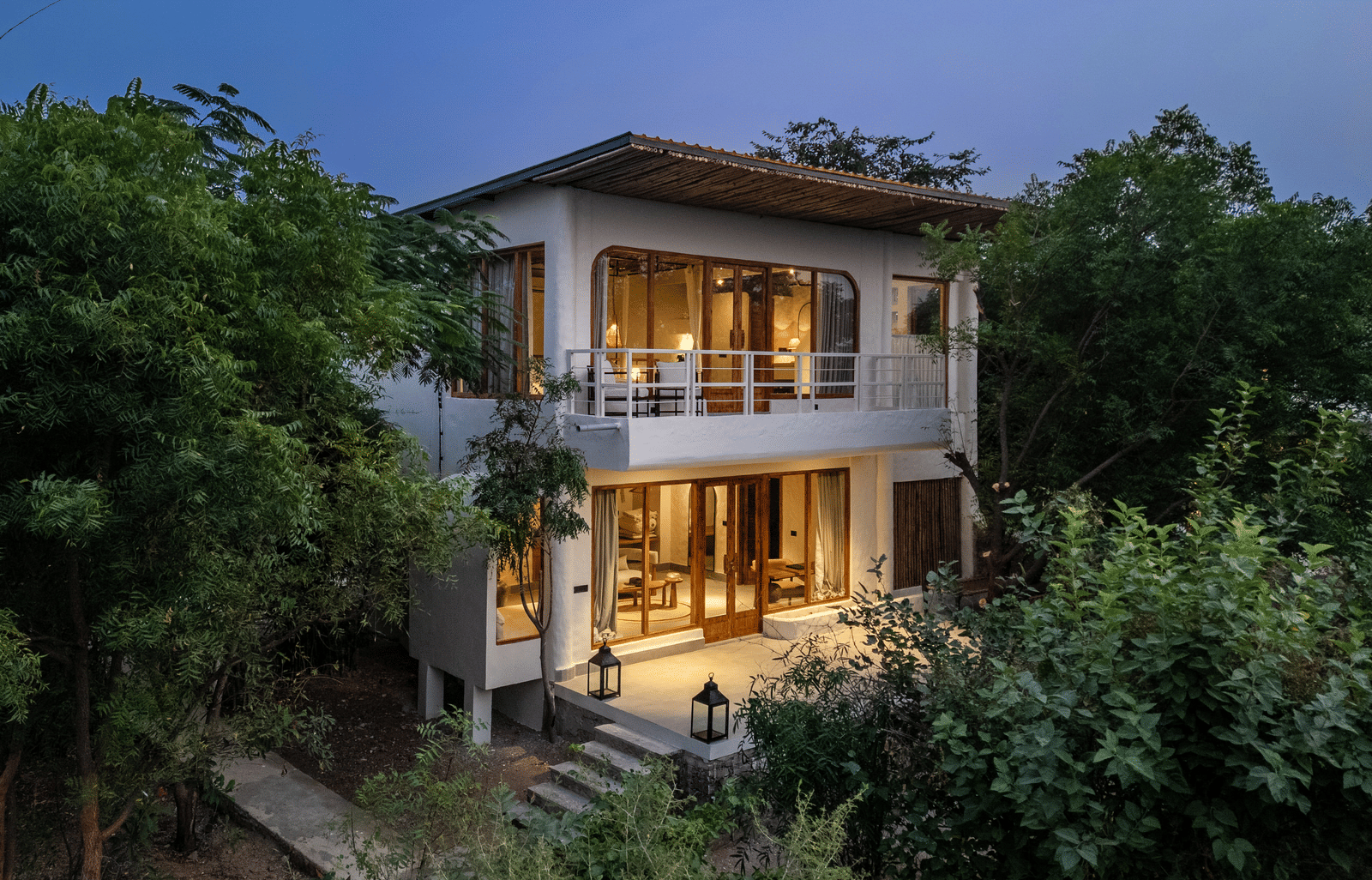 Exterior of a Forest villa surrounded by plants and trees in daylight.
