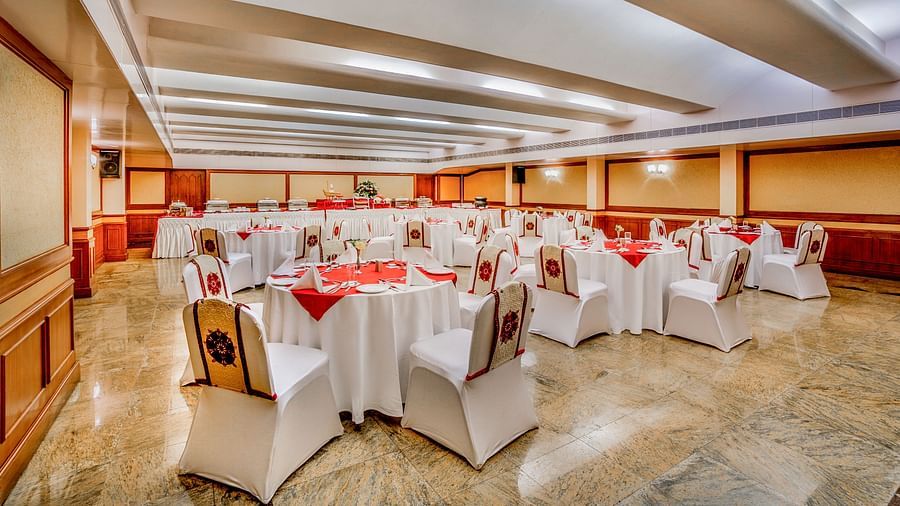 A spacious banquet hall with white-clothed tables and comfortable seating, ready for an event. - Tara, Comfort Hotel in Hyderabad - Ramoji Film City.