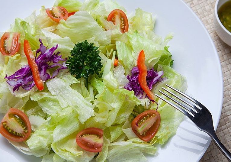A close-up of a salad with lettuce, tomatoes, and herbs - Shreyas Retreat