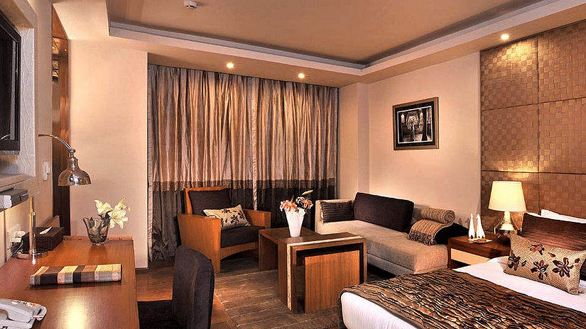 An image of a bedroom featuring a bed, a seating area with sofa, a cabinet table, a flat TV screen, etc at Udman Grand Mashobra