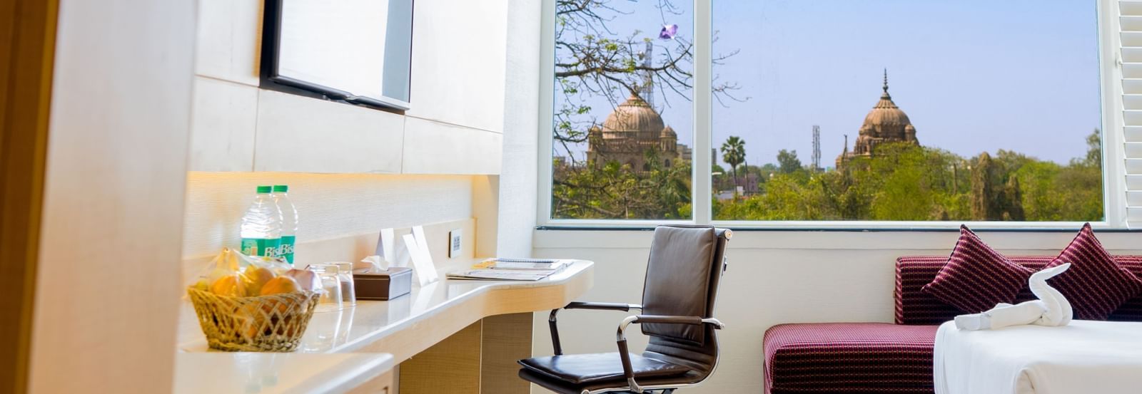 An entrance view of a room with a desk, twin beds, chair, seating area, and a huge window | Gemini Continental