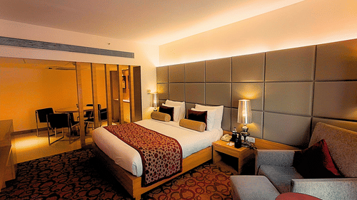 Premium hotel room with elegant decor, plush seating, and ambient lighting at Pride Plaza Ahmedabad