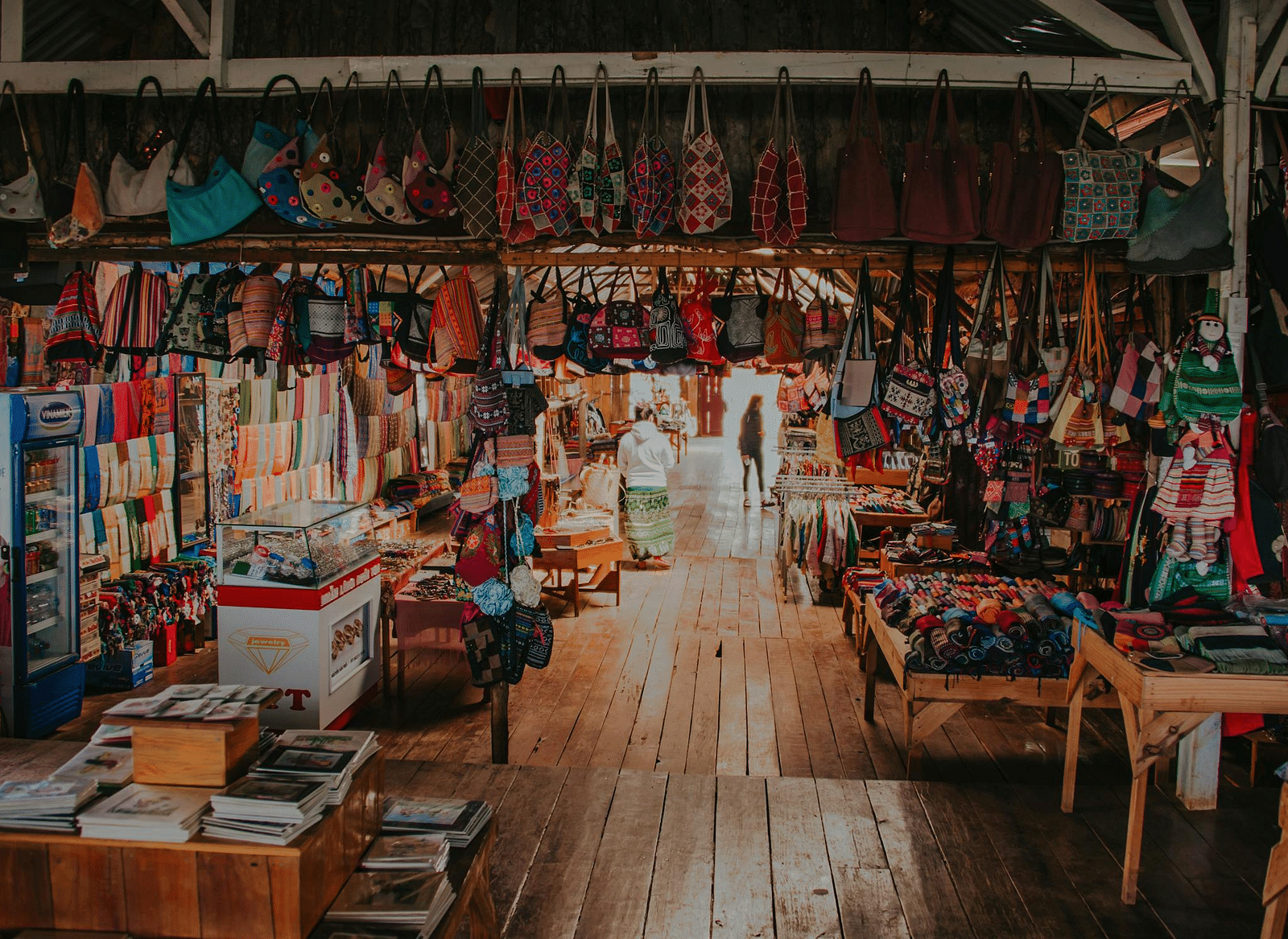 A lively indoor market filled with handcrafted goods, including textiles, wooden crafts, and souvenirs