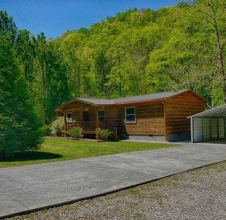exterior shot of the river cabin taken from a distance featuring a huge evergreen conifer tree in front of it - Historic Tapoco Lodge