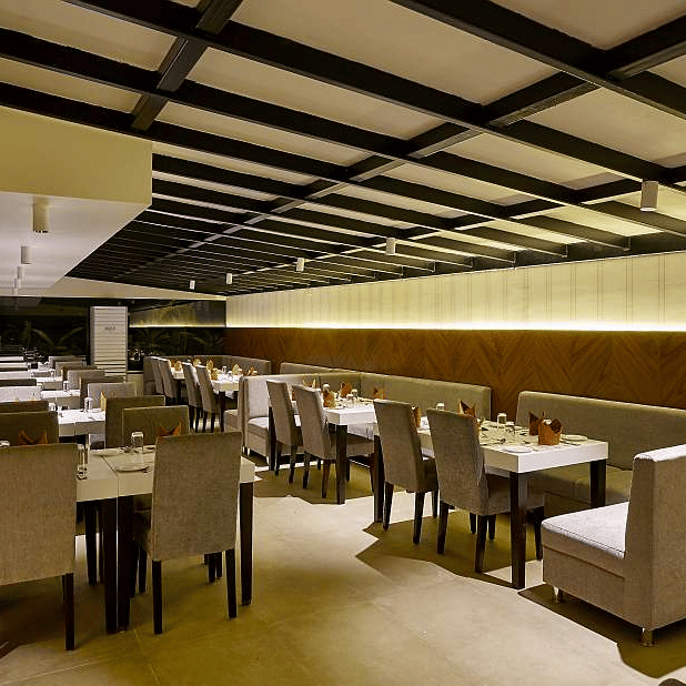 A restaurant interior with dark ceilings, square patterns, and a spacious dining area at The Citrine.