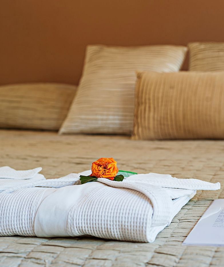 Close-up of towels arranged with flower petals on a bed - Shreyas Retreat