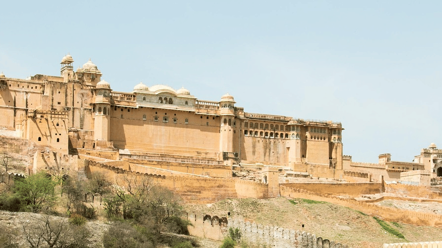 Panoramic view of a massive stone fort along the edge of a dry, rocky hillside