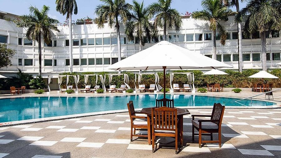 Swimming pool with seating area besides it at The Claridges New Delhi