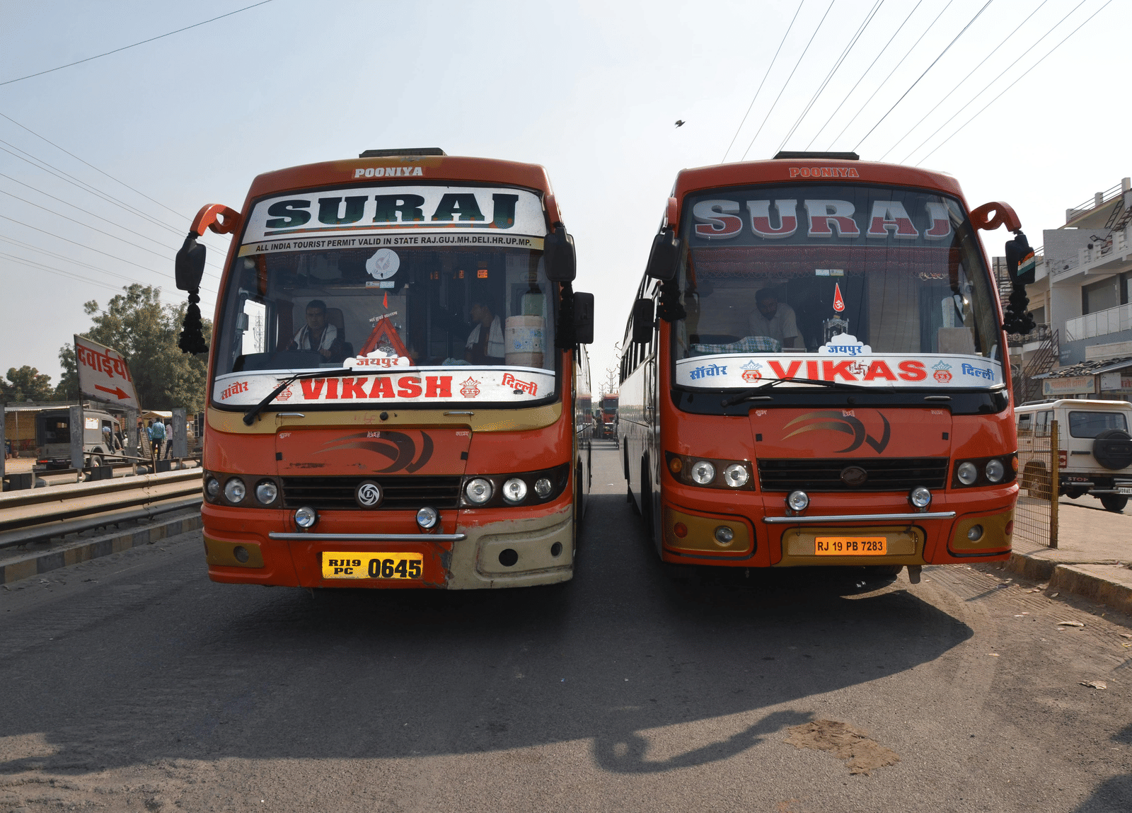 Two colourful intercity buses parked at a roadside.