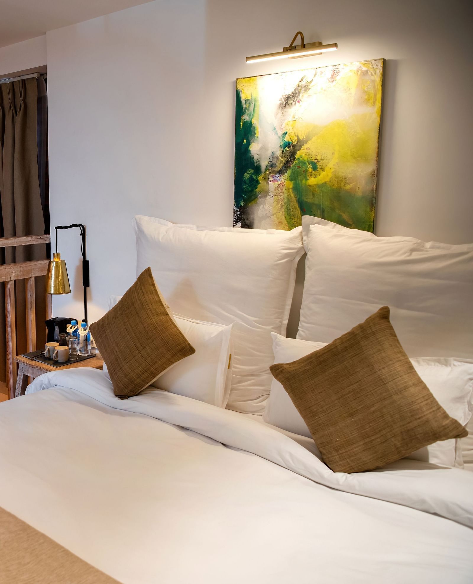 Loft suite where a staircase is leading to it featuring a bed, pillows, and wall hangings - The Nanee