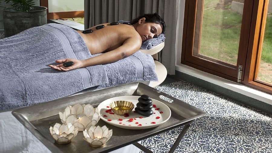 A person receiving a massage on a table, tray with items, indoor setting - Shreyas Retreat