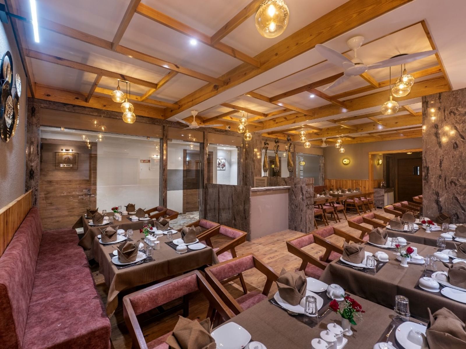 A dining area with multiple tables and chairs set under warm lighting at Angel Lords Eco Inn Amreli.