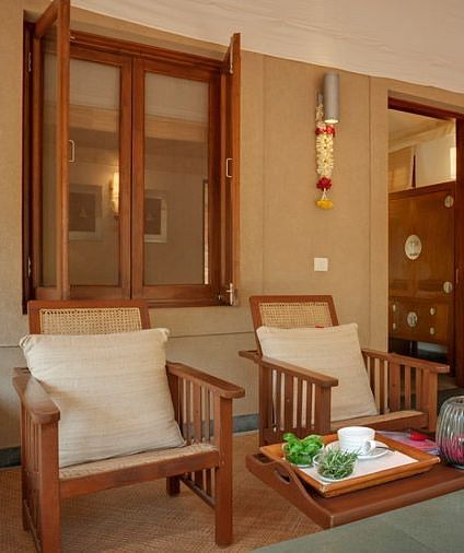 A living room with a couch, chairs, and a view of a garden - Shreyas Retreat