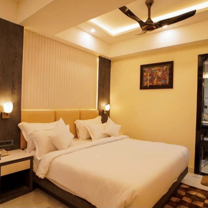 A bedroom showcasing plush bed with pillows, ceiling fan, artwork, and sliding balcony doors.