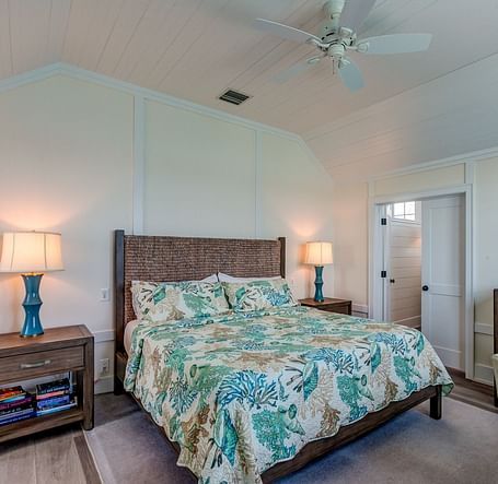 Bedroom with a patterned bedspread, wooden furniture, and a ceiling fan | Abaco Inn