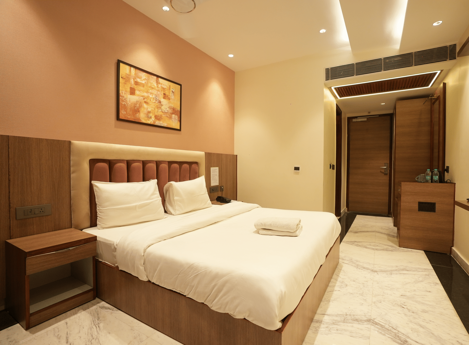 Bed and bright accent wall decor with a minibar station at Lime Tree Hotel Near India Expo Mart, Greater Noida.