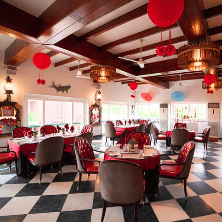 Vibrant cafe or dining area decorated with red chairs and accents, featuring a distinctive black and white tiled floor pattern.