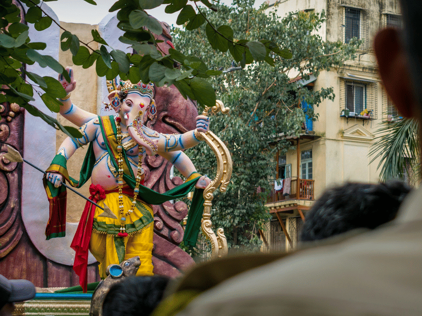 An idol of a deity in the city, surrounded by people.