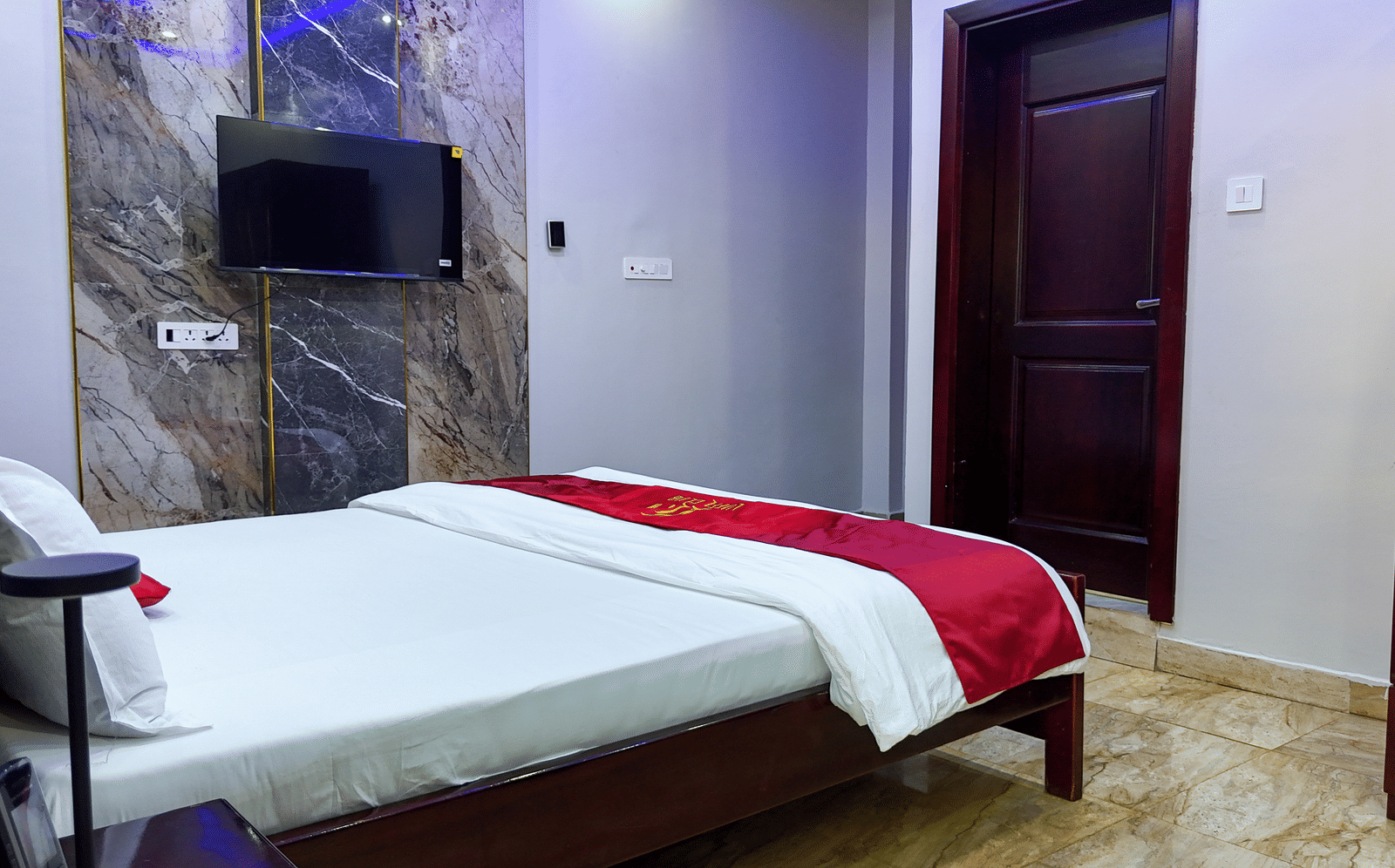 Minimalist room interior with a bed, wall-mounted TV, and closed door - Luffu Club