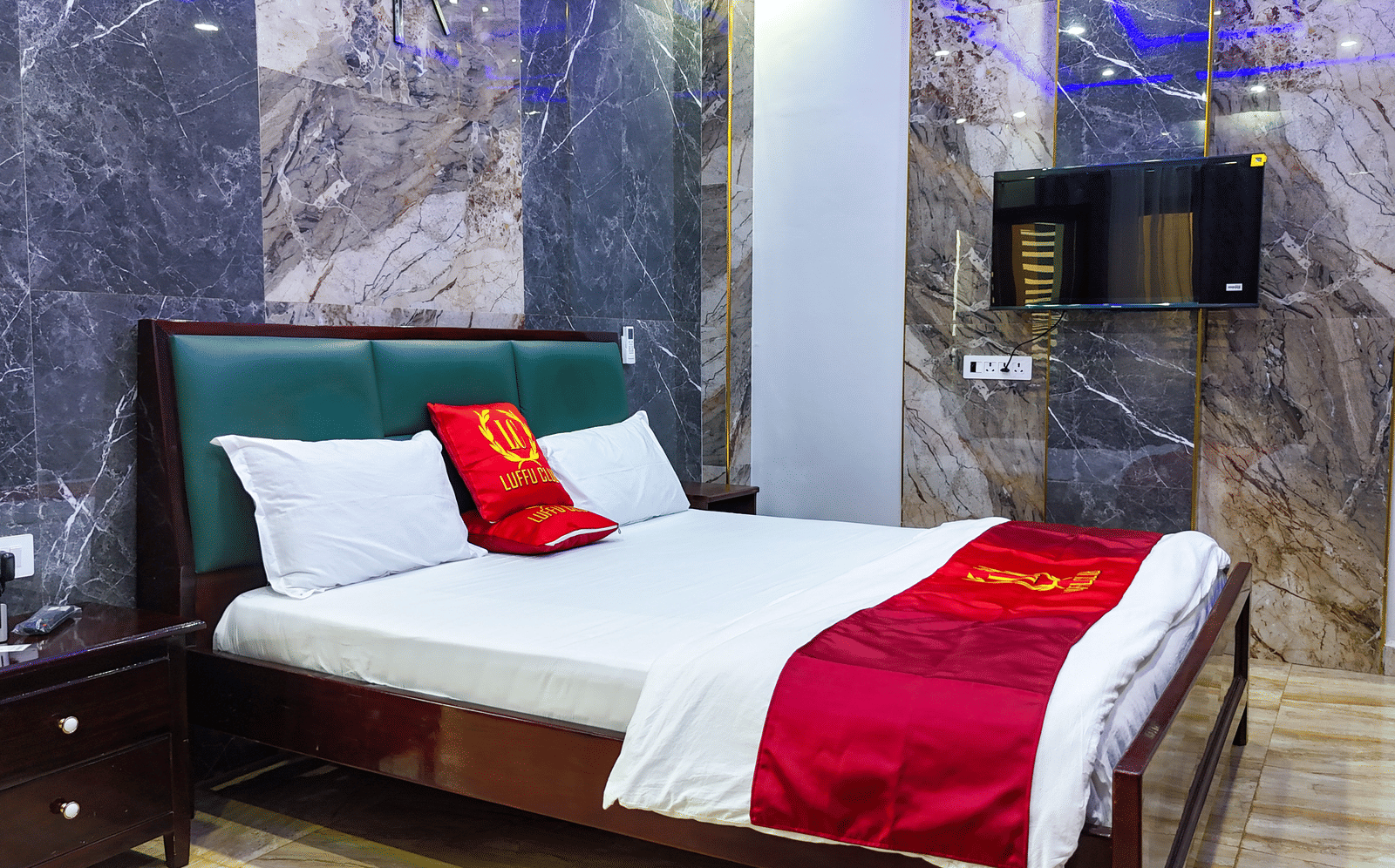 Room with a bed, red accents sheets, and marble-style wall panelling - Luffu Club