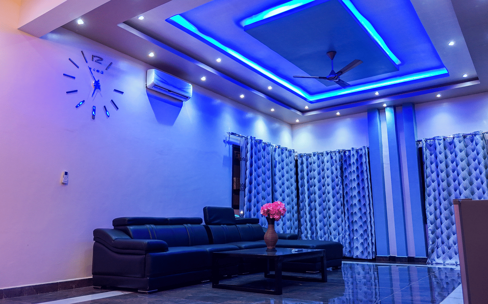 Spacious living room with blue ceiling lights, sofa, and ceiling-to-floor curtains - Luffu Club
