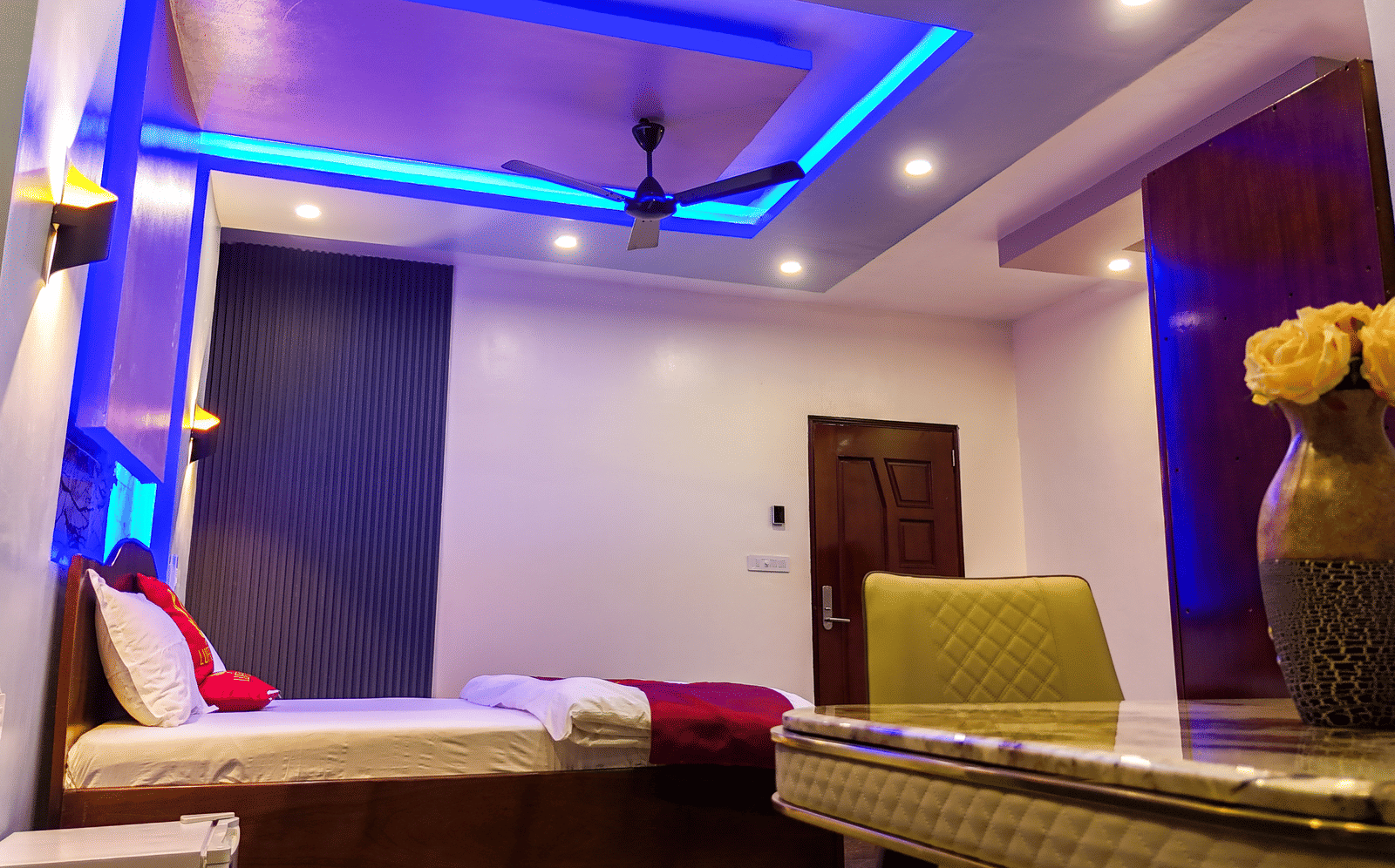Room with blue and purple accent lighting, double bed and seating area - Luffu Club