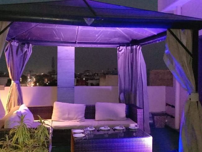 Tables and chairs are arranged below the curtain-draped top and pillars at Hotel Uday Palace.