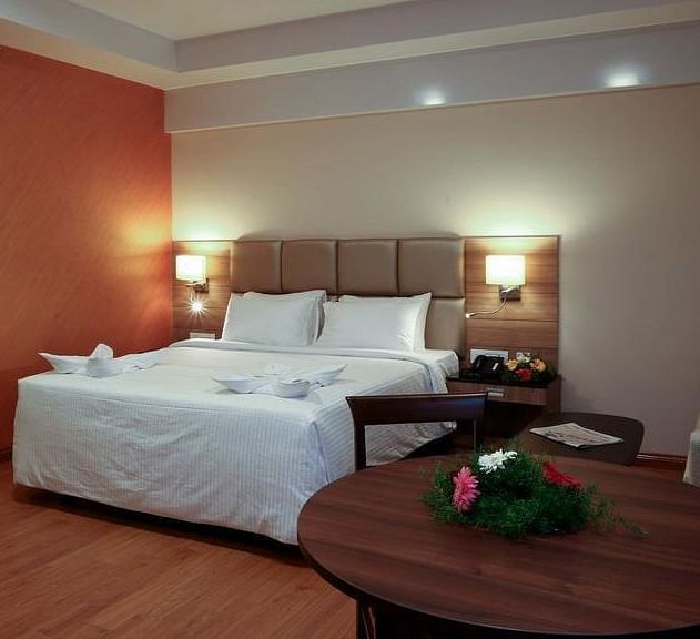 Room with bed and a table with flowers on top at Fressotel Seetharam, Coimbatore