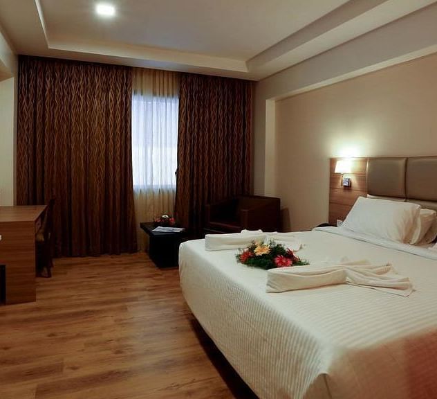 Spacious room with television, bed and table at Fressotel Seetharam, Coimbatore