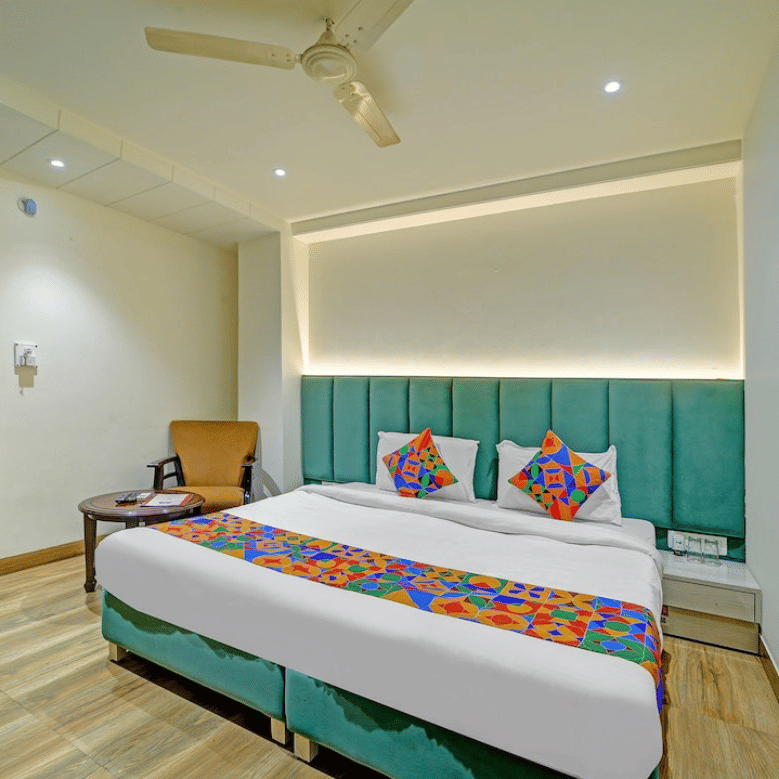 Contemporary deluxe room with twin beds, teal accent wall and warm lighting at Hotel Maurya, Bhopal.