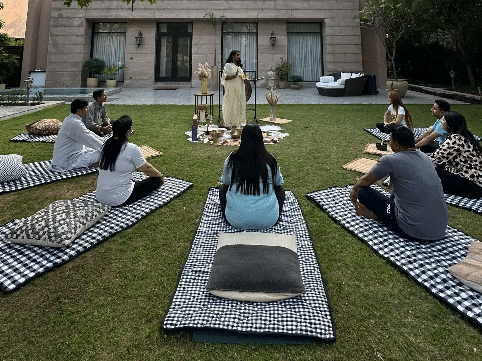 Guests seated on mats in a lawn area for an outdoor session at Karma Chalets.