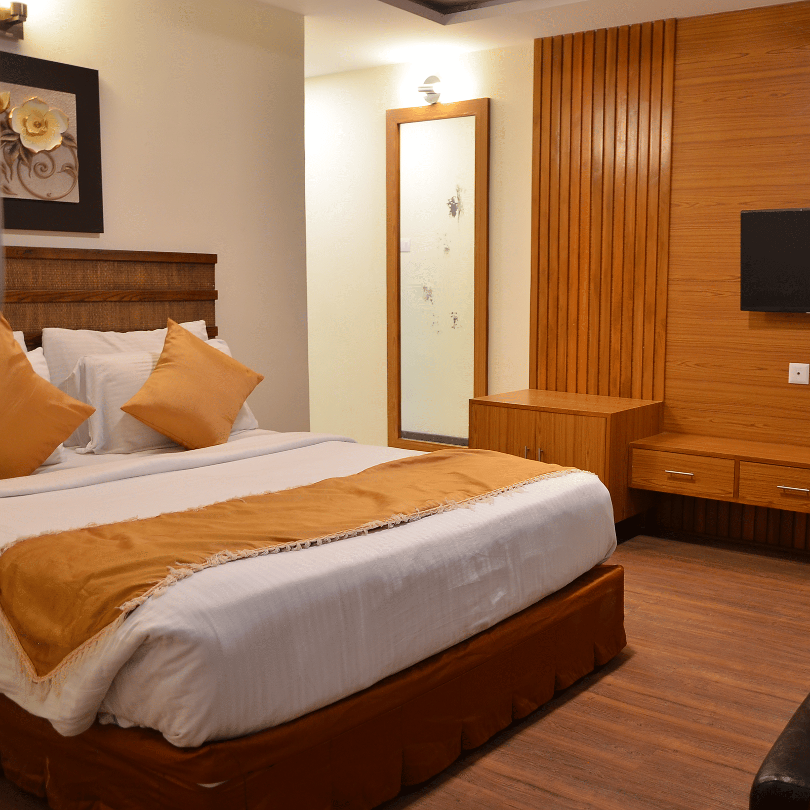 An elegant room with a queen bed, wooden furnishing, and a wall-mounted TV for a relaxing stay - Benzz Park, Kodaikanal