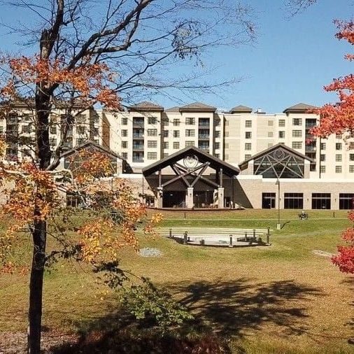 The exterior view of YO1 Longevity & Health Resorts during the fall season, surrounded by colourful autumn trees under a clear blue sky.
