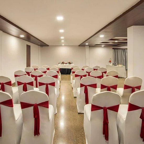 Banquet hall setup featuring  ample seating arrangement, bright lighting, and wooden flooring at Lords Eco Inn Jayanagar Bangalore.