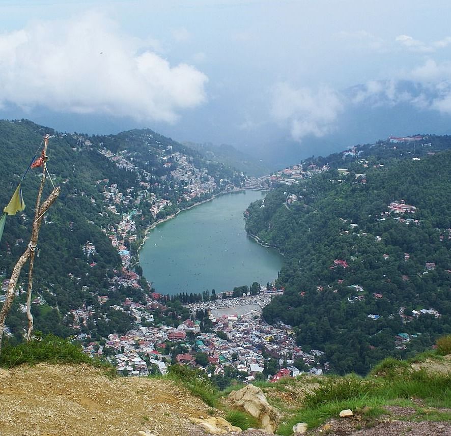 A view of a valley with a lake in the middle of image, alongside a small village, in the midst of the moody mists.