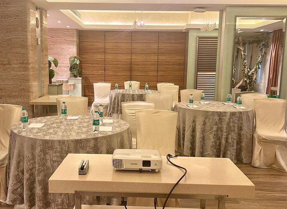 Conference-style setup with covered chairs and a central projector on a table at Mirage Hotel, Mumbai.