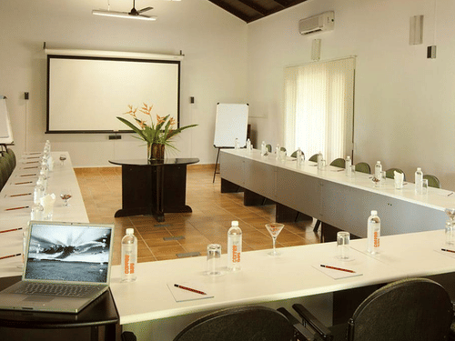 Conference Hall in Bandipur at The serai Bandipur with a U-shaped table and a projector screen under warm lighting