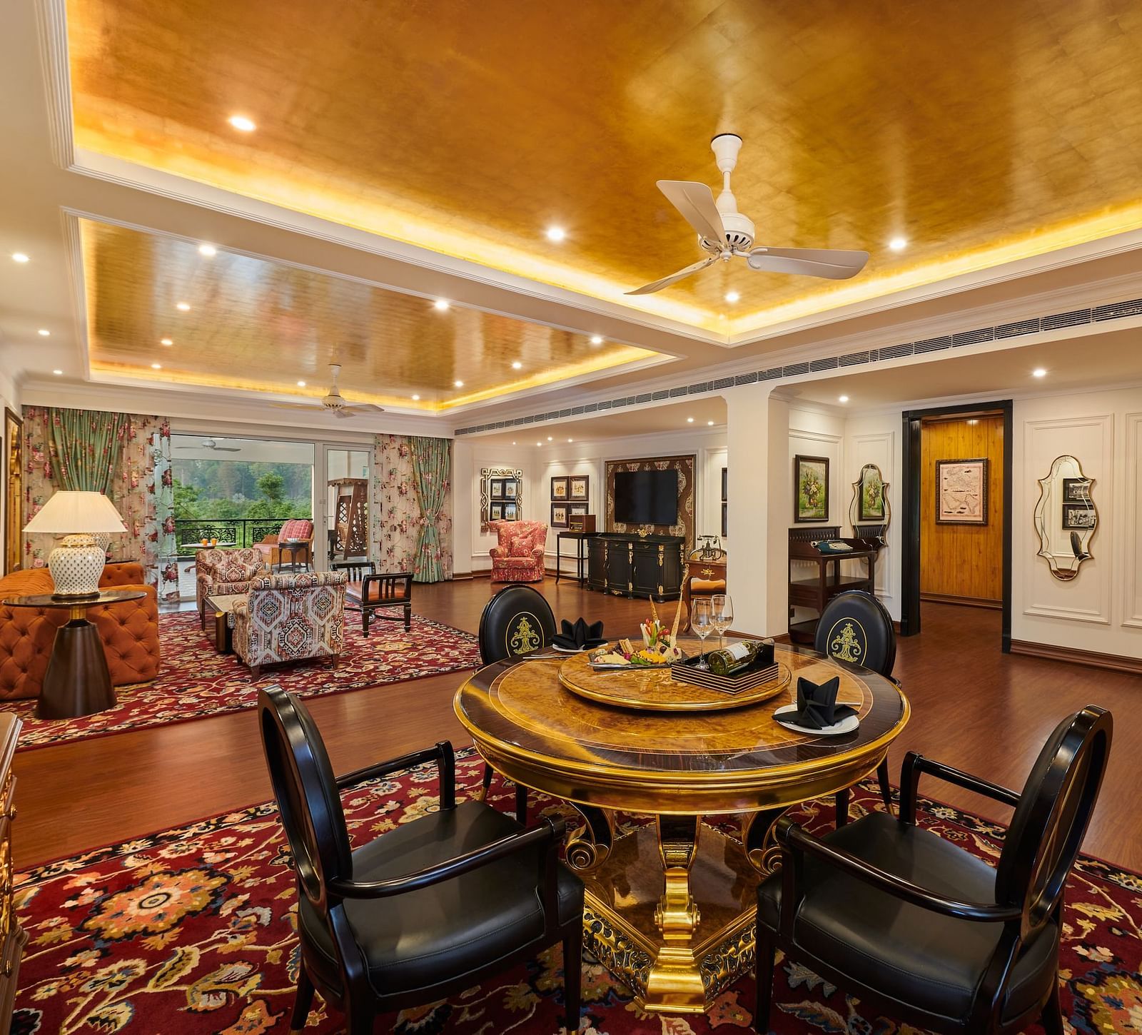 Spacious dining area with round table, chandeliers, and rich artwork.