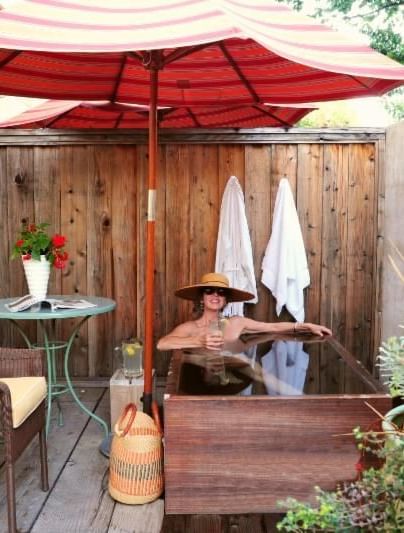 A private patio at Serenite Hotels featuring a small table with a flowerpot, 2 chairs, an umbrella, and towels neatly hanging on a wooden fence in the background