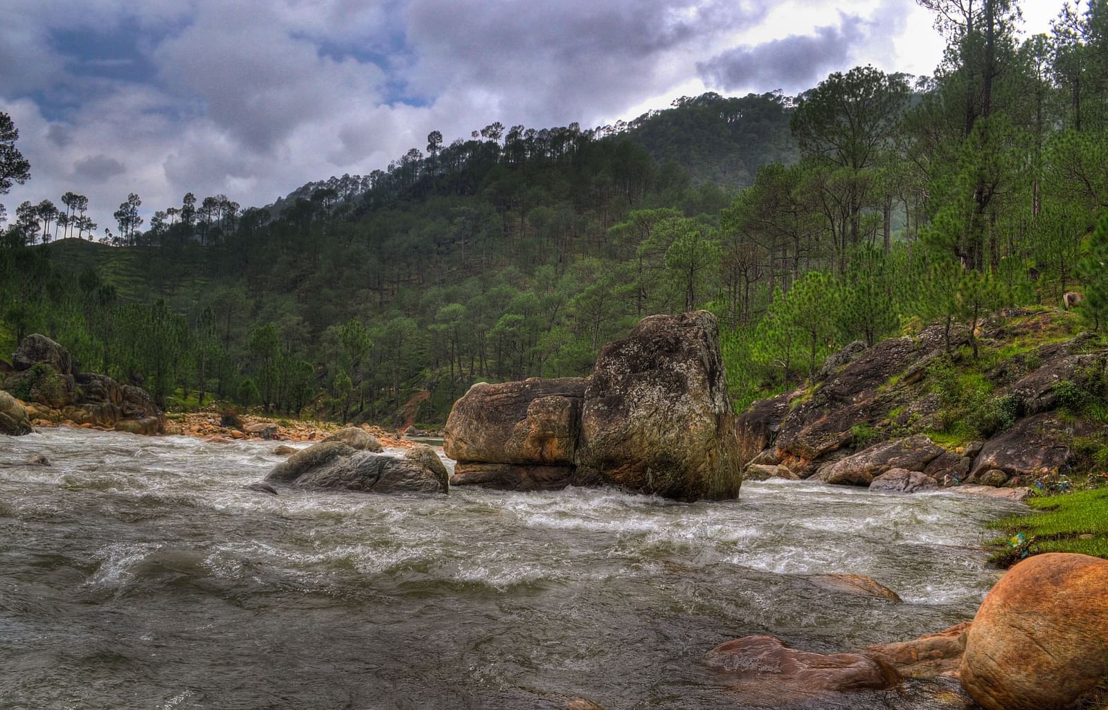 An image of a stream filled with stones and a mountain at the distance