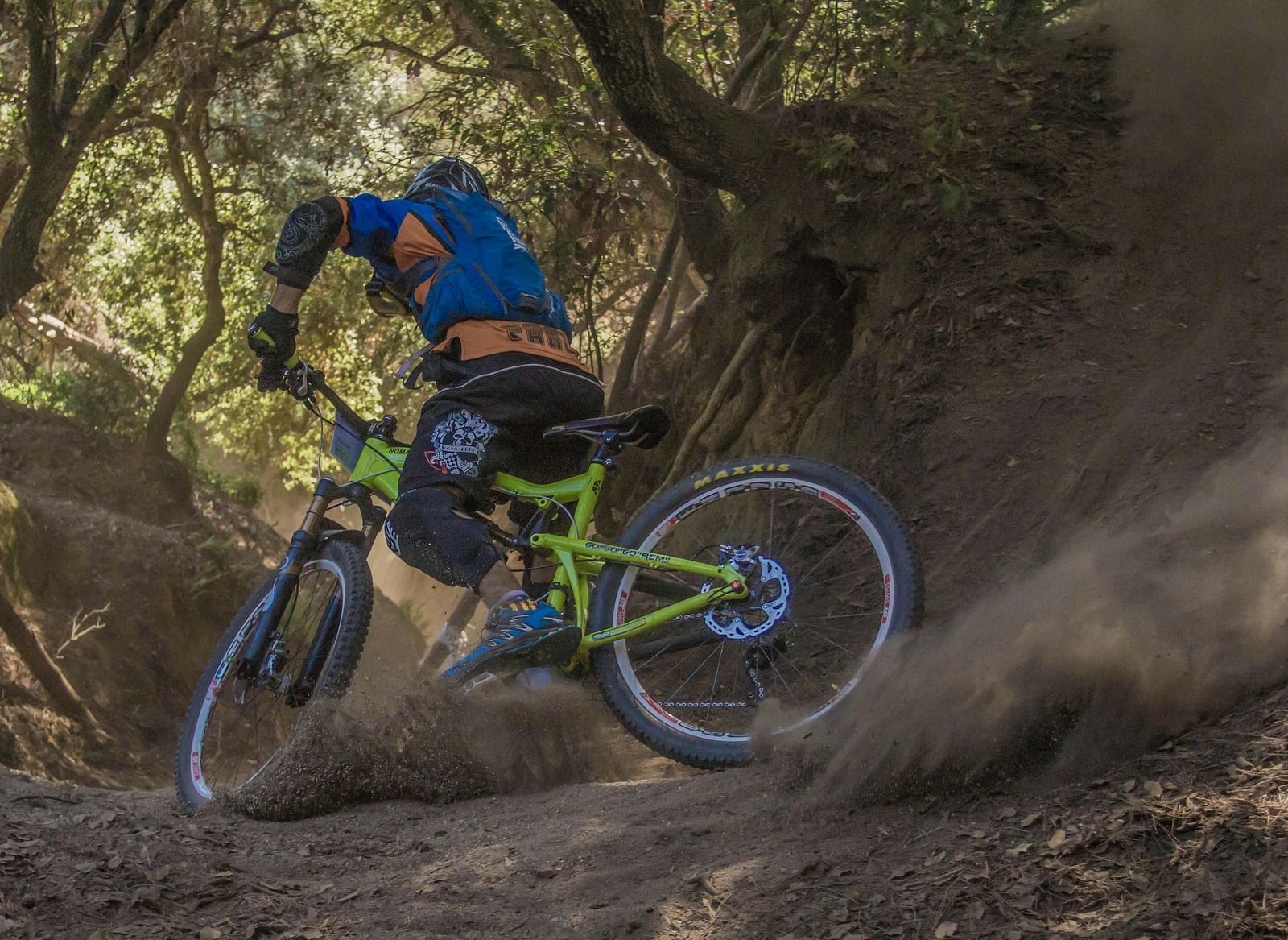 A man cycling on an off road surrounded by a forest.
