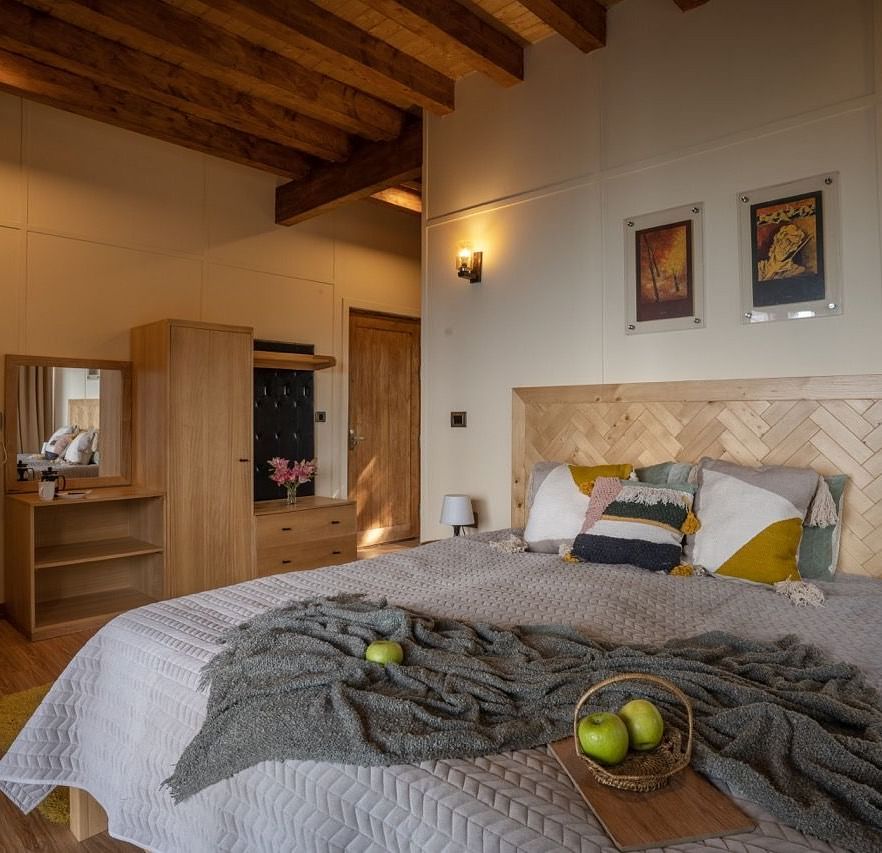 An image of a bedroom with king size bed, frames on the wall, a dressing table, a cabinet at Avalon Cottages, Kanatal