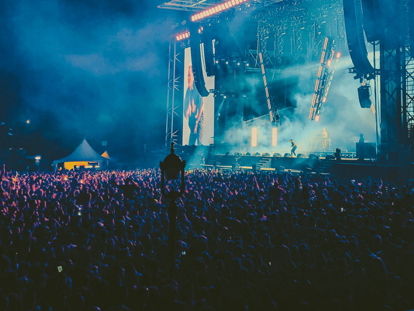Open-air concert stage lit up at night with a cheering crowd in front