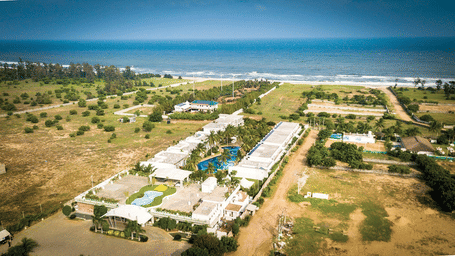 An aerial view of Grande Bay Resort & Spa, one of the best Mamallapuram resorts, featuring the blue sky & ocean stretching towards the horizon.