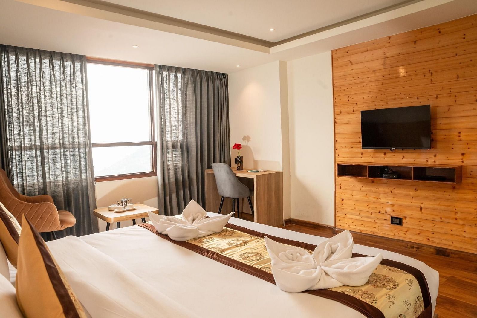 A wall-mounted television with a double bed placed opposite to it in a Premium Room at Sumitel Sanderling.
